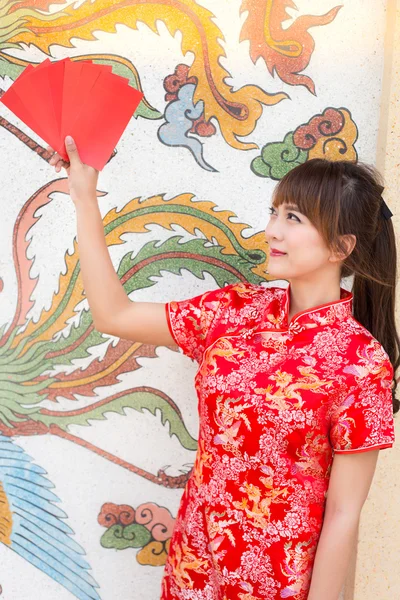 Frohes chinesisches Neujahr, niedlich lächelnde asiatische Frau kleidet traditionelles Cheongsam und Qipao hält rote Umschläge ang pow oder rotes Päckchen Geldgeschenkkarte auf chinesischem Muster traditionellen Hintergrund — Stockfoto