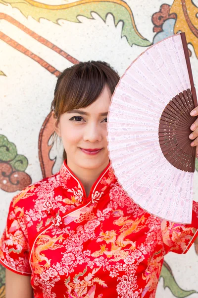 Schöne asiatische Frau trägt traditionelles Cheongsam auf chinesischem Muster traditionellen Hintergrund — Stockfoto