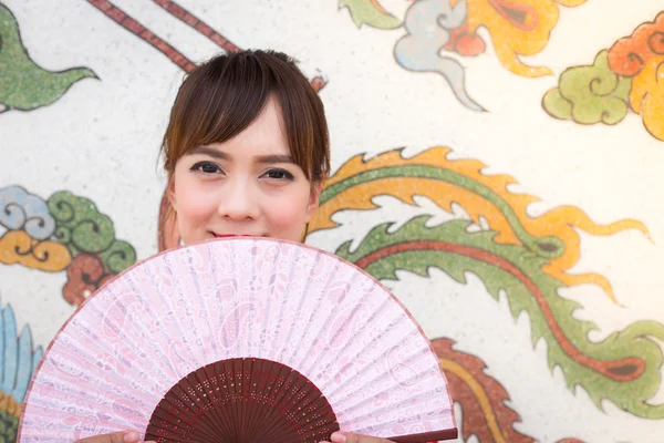 Beautiful Asian woman wearing traditional Cheongsam on chinese pattern traditional background — Stok fotoğraf