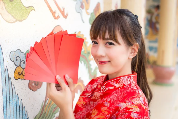 Frohes chinesisches Neujahr, niedlich lächelnde asiatische Frau kleidet traditionelles Cheongsam und Qipao hält rote Umschläge ang pow oder rotes Päckchen Geldgeschenkkarte auf chinesischem Muster traditionellen Hintergrund — Stockfoto