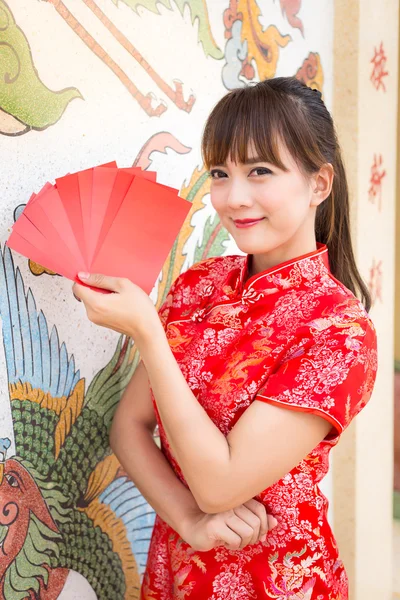 Felice anno nuovo cinese, Carino sorridente donna asiatica vestito tradizionale cheongsam e qipao in possesso di buste rosse ang pow o pacchetto rosso carta regalo monetaria sul modello cinese sfondo tradizionale — Foto Stock