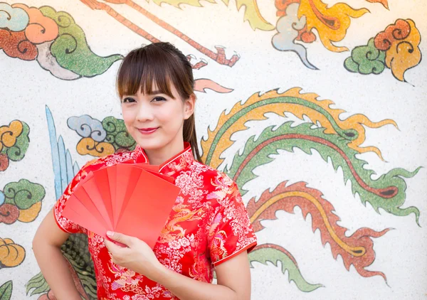 Happy chinese new year,Cute smiling Asian woman dress traditional cheongsam and qipao holding red envelopes ang pow or red packet monetary gift card on chinese pattern traditional background — Φωτογραφία Αρχείου