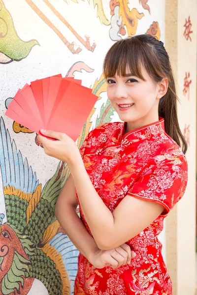 Frohes chinesisches Neujahr, süße lächelnde asiatische Frau kleidet traditionelles Cheongsam und Qipao hält rote Umschläge ang pow oder rotes Päckchen Geldgeschenkkarte auf chinesischem Muster — Stockfoto