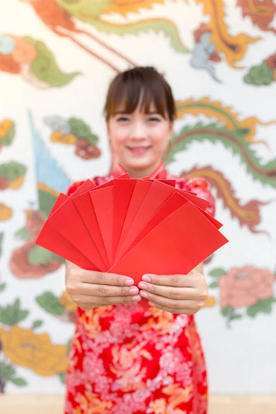 Frohes chinesisches neues Jahr, süße lächelnde asiatische Frau kleidet traditionelles Cheongsam und Qipao hält rote Umschläge ang pow oder rotes Päckchen Geldgeschenkkarte auf chinesischem Muster traditionellen Hintergrund auswählen Fokus rote Karte — Stockfoto