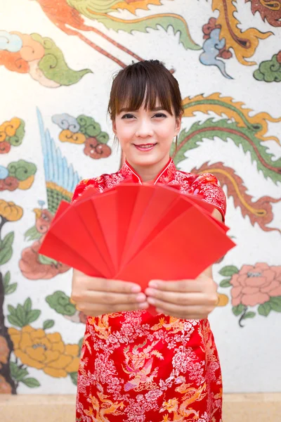 Glückliches chinesisches neues Jahr, niedlich lächelnde asiatische Frau kleidet traditionelles Cheongsam und Qipao hält rote Umschläge ang pow oder rotes Päckchen Geldgeschenkkarte auf chinesischem Muster traditionellen Hintergrund auswählen Fokus Gesicht Modell — Stockfoto