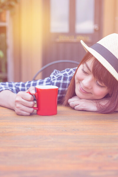wear hat woman sitting in outdoor with warm drink relax pastel color tone
