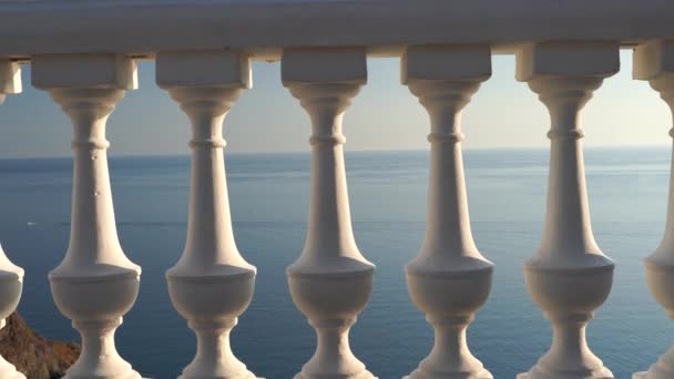 Κλασσικό balustrade στο ανάχωμα με τη θάλασσα. Λευκό μπαλκόνι πάνω από τη θάλασσα. Πεζόδρομος με όμορφη θέα στη θάλασσα σε μια καθαρή μέρα. Κοντινό πλάνο του βάλσαμου δίπλα στη θάλασσα. 4K — Αρχείο Βίντεο