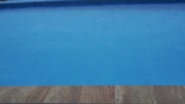 Zomer regen spat in het zwembad. Close-up van het zwembad tijdens storm en regendruppels die in het water vallen — Stockvideo