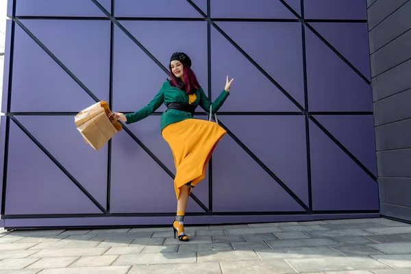 Una chica adicta a las compras lanza sus maletas cerca de un centro comercial. Diviértete de compras el Viernes Negro. la chica en la tienda está contenta con sus compras, lanza paquetes. Concepto consumidor. — Foto de Stock