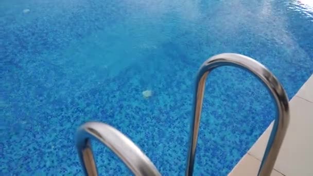 Открытый бассейн с рябью голубой бирюзовой водой и стальными перилами лестницы. Лестница из нержавеющей стали для спуска в бассейн. — стоковое видео