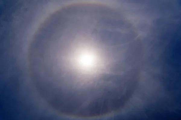 Fantastic beautiful sun halo phenomenon in the blue sky. Rainbow in the form of a circle around the sun.