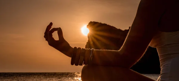 Banner. Jovem praticando ioga na praia com pôr do sol. Mantém os dedos ligados, o sol brilha através deles. O conceito de um estilo de vida saudável, harmonia. — Fotografia de Stock