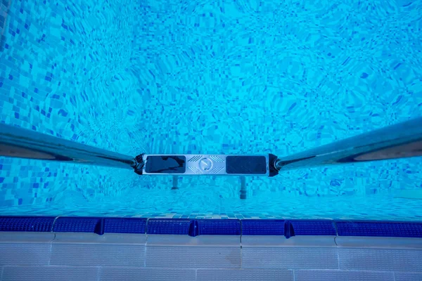 Hintergrund des blauen, transparenten Wassers im Schwimmbad auf dem Hotelgelände. Abstieg zum Pool mit Geländern. Ruhe- und Entspannungskonzept. Aktive Erholung am Meer — Stockfoto