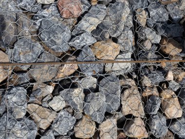 Sıkıca inşa edilmiş kaya ve tellerden oluşan bir duvar..