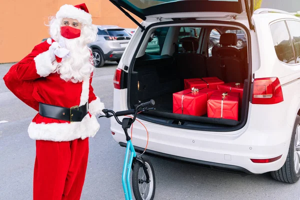 Noel Baba 'nın portresi hediyelerle dolu. Hediyeleri dağıtmak için büyük tekerlekli bir scooter' ı var. Çünkü arabası bozulmuş ve Coronavirus Covid19 salgınından dolayı maske takıyor.