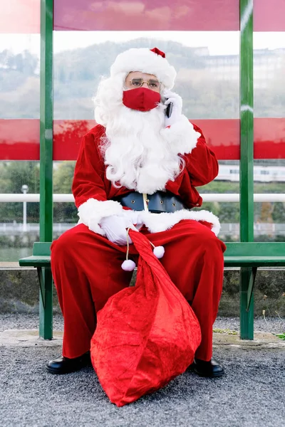 Portret Wyprostowanego Mikołaja Siedzącego Przystanku Autobusowym Rozmawiającego Telefonem Komórkowym Noszącym — Zdjęcie stockowe