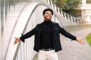 Kolları açık yakışıklı bir Faslı 'nın şık portresi. Şehir tarzı kıyafetlerle gülümsüyor ve mutlu görünüyor.