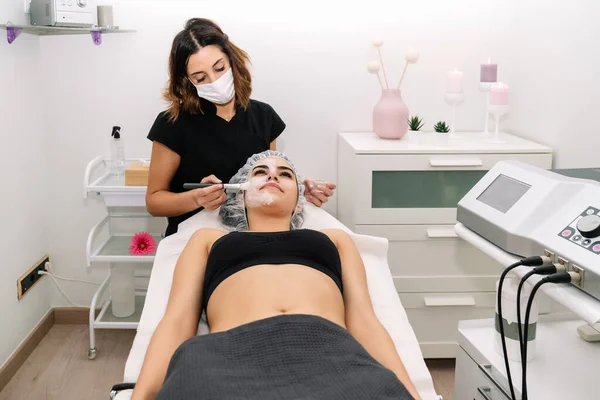 Kosmetolog Som Ger Ansiktsmask Till Vacker Ung Kvinna Som Njuter — Stockfoto