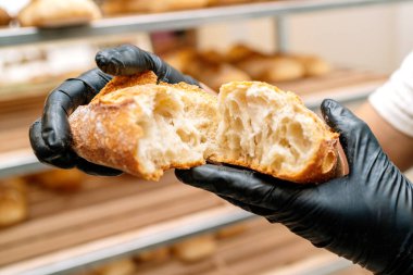 Han of Baker 'ın seçici odak noktası, bir somun ekmeğin kırıntılarını elleriyle nasıl keseceğini ve siyah eldivenlerle nasıl korunacağını gösteriyor.