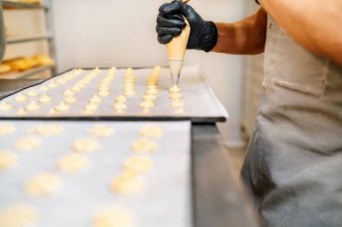 Pasta dükkanında krema sıkan bir hamur işi şefinin ellerinin seçici odağı.
