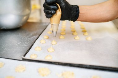 Pasta dükkanında krema sıkan bir hamur işi şefinin ellerinin seçici odağı.