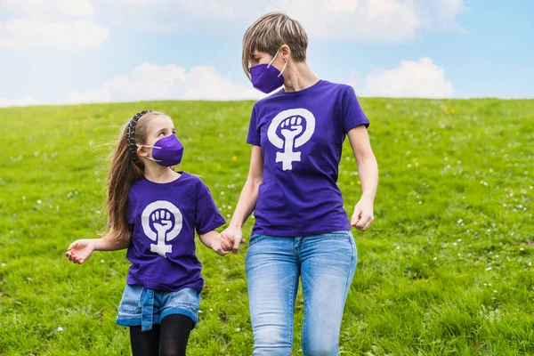 girls from a family wearing a purple T-shirt with the symbol of the working woman claiming women\'s rights for International Women\'s Day on March 8 and wearing a face mask for the coronavirus pandemic