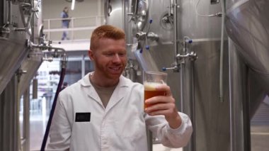 Modern bir bira fabrikasında içmeden önce beyaz önlüklü profesyonel bira ustası zanaat birasının kalitesini, rengini ve kokusunu inceliyor.