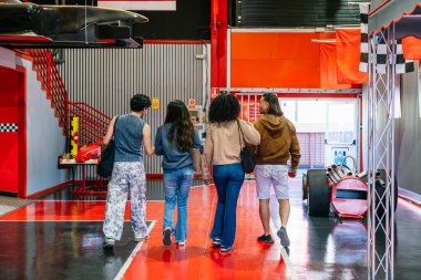 Bir grup farklı arkadaş modern bir kapalı alan go kart tesisinde yürüyor ve eğleniyorlar. Yarış etkinliğine hazırlanıyorlar.