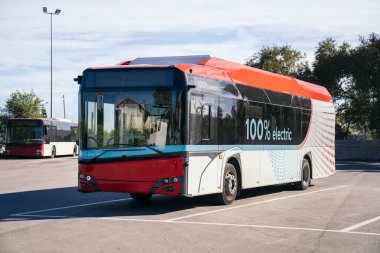 Sıfır emisyonlu elektrikli şehir otobüsü, sürdürülebilir toplu taşımayı temsil eden, modern bir şehir tesisinde park edilmiş.