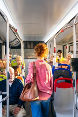 Modern bir şehir otobüsünde seyahat eden çeşitli insanlar. Toplumları birbirine bağlayan toplu taşımacılık ve kentsel hareketliliği teşvik