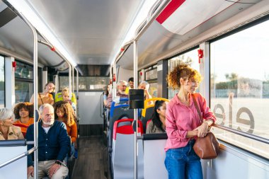 Toplu taşıma araçlarına binen, pencereden dışarı bakan veya etkileşime giren farklı yaş ve etnik kökenlere sahip banliyö sakinleri. Kentsel yaşam tarzı konsepti