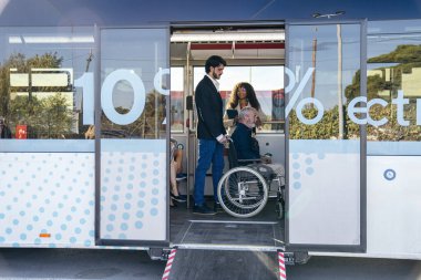 Umumi bir otobüste yaşlı bir adama yardım eden genç adam kentsel hareketlilik için ulaşılabilir bir rampa kullanıyor.