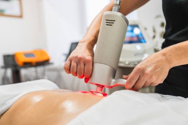 Kadın, vücut terapisi için kafası dönen profesyonel bir makine kullanarak derin bir fizyoaktif masaj yaptırıyor.