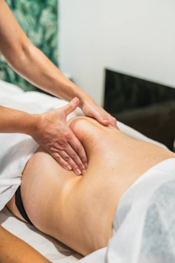 Profesyonel terapist elleri bir kadına derin bir karın masajı yapar, sağlık, rahatlama ve vücut bakımına odaklanır.