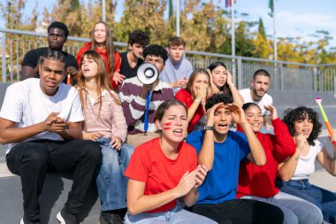 Stadyumda takımlarını destekleyen çok ırklı gençler, spor müsabakalarını izlerken güçlü duygular ifade ediyorlar.
