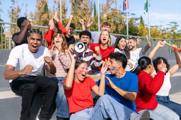 Çok ırklı gençler tribünlerden takımlarını aktif olarak destekliyor, heyecan ve coşku ifade ediyorlar.