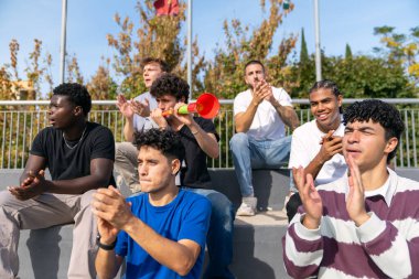 Çok ırklı arkadaşlar destek ve coşku gösteriyorlar, stadyumdan bir spor etkinliğini alkışlıyorlar ve izliyorlar.