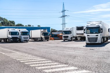 Dondurulmuş kamyonlar depo tesisinin önüne park edilmiş. Malların tedarik zinciri ve dağıtımını gösteriyor.