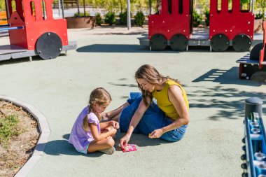 Kafkas anne ve kızı güneşli yaz gününde oyun parkında birlikte tik taktik parmak oynuyorlar.