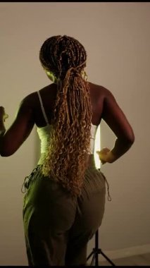 Uzun örgülü, enerjik dans eden mutlu Afrikalı Amerikalı kadın. Stüdyoda modern korku dansı yapan etkileyici bir bayan dansçı.