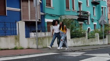 Genç Afro Latin çift mutlu bir şekilde dans ediyor ve Avrupa sokaklarında yürüyor. Romantik ve neşeli kadın ve erkek dışarıda birlikte eğleniyorlar.
