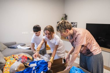 Anne ve çocuklar renkli karnaval kostümleri ve aksesuarlarıyla dolu karton kutuları boşaltıp evde yapılacak kıyafet partisine hazırlanıyorlar.
