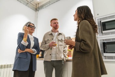 Modern bir ofis dinlenme odasında çeşitli profesyoneller iletişim kuruyor ve tartışıyorlar, işbirliği ve takım iletişimini teşvik ediyorlar.