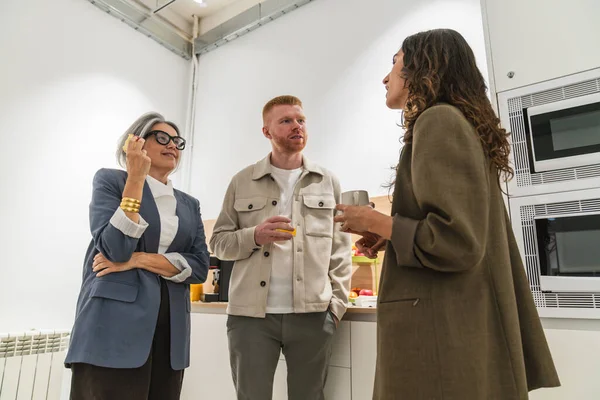 Modern bir ofis dinlenme odasında çeşitli profesyoneller iletişim kuruyor ve tartışıyorlar, işbirliği ve takım iletişimini teşvik ediyorlar.