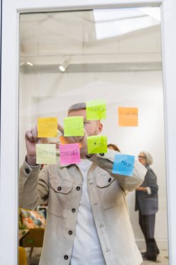Girişim planlama stratejisi, toplantı sırasında cam bir tahtaya renkli yapışkan notlar üzerine yaratıcı fikirler yazmak.