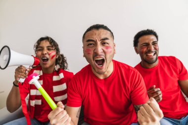 Çok ırklı arkadaşlar kutlama yapıp çığlık atıyorlar. Evde spor müsabakalarını izliyorlar. Takımlarına heyecan ve destek gösteriyorlar.