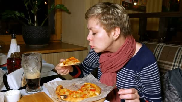 Mooie blonde vrouw eet pizza en bier drinken — Stockvideo