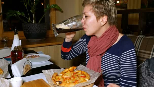 Söt blond kvinna äter pizza och dricker öl — Stockvideo