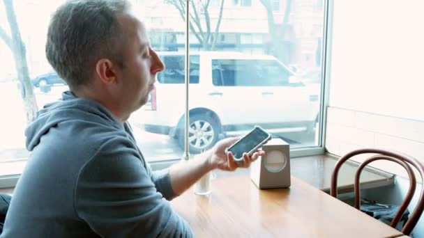 Hombre mensajes de texto y navegación con la aplicación móvil en un café — Vídeo de stock