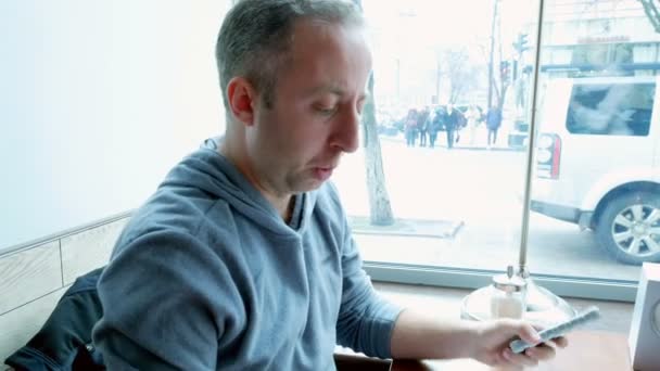 Hombre ordena en un restaurante cafetería y mensajes de texto móvil — Vídeos de Stock
